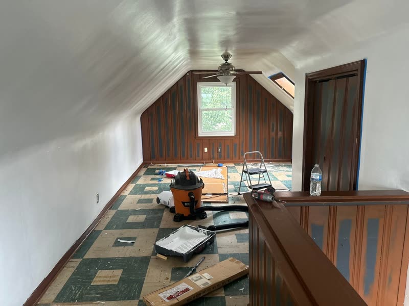 Attic bonus room before — old green tile floor, dated paneling and tools